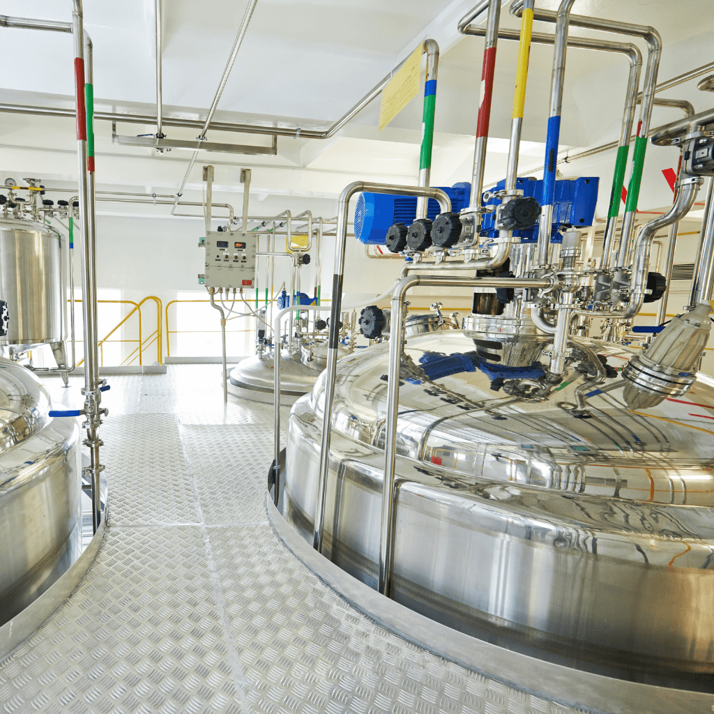 Stainless steel industrial mixing tanks with piping and process equipment in manufacturing plant